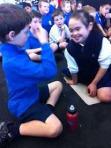 Students facing each other signing, with other children behind them