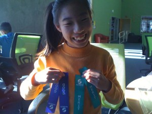 Grace standing holding her gymnastics awards